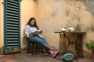 Woman in White Long Sleeve Shirt and Blue Denim Jeans Sitting on Black Wooden Chair